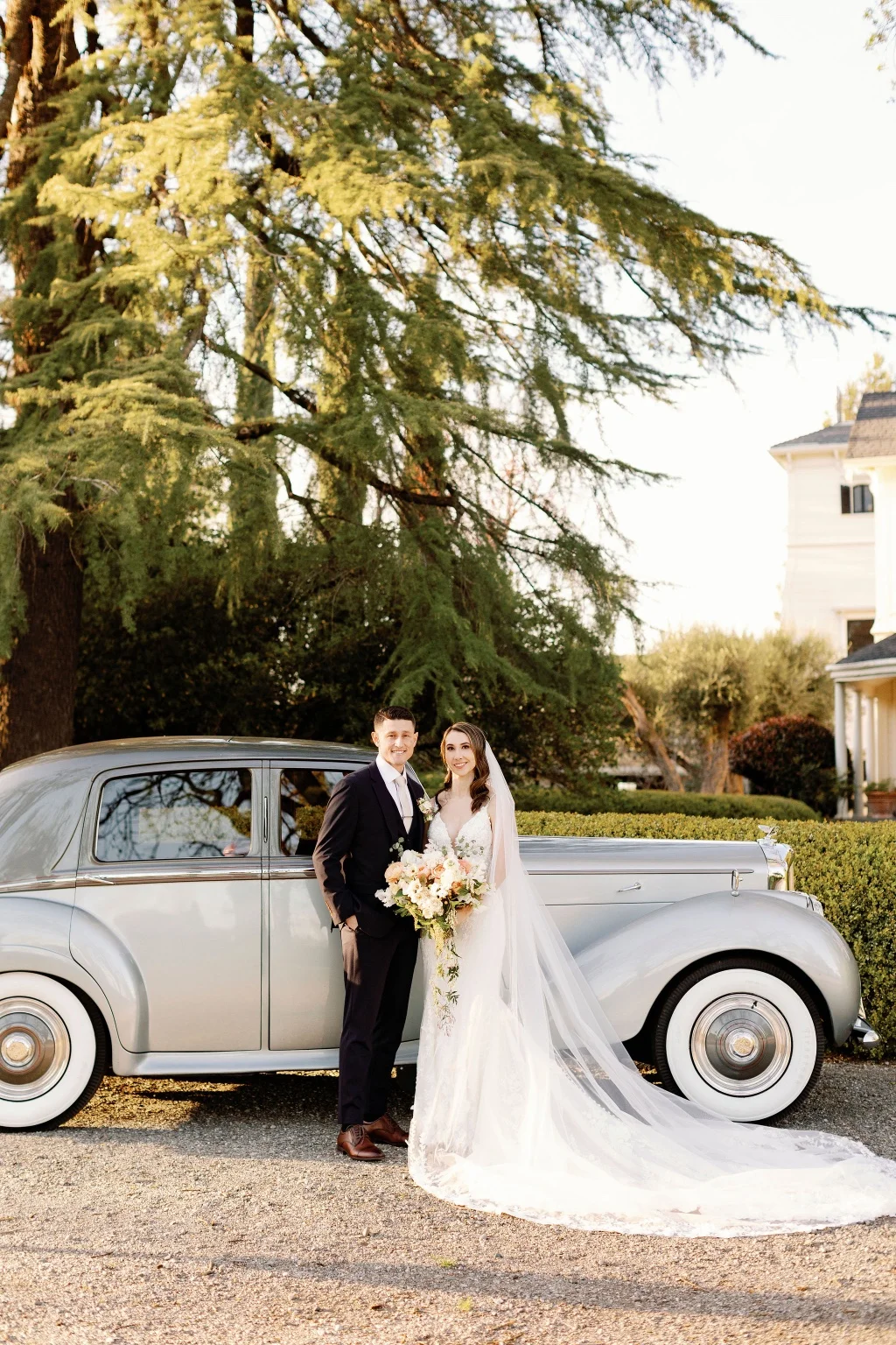 A wedding couple beside the platinum Bentley in golden afternoon light